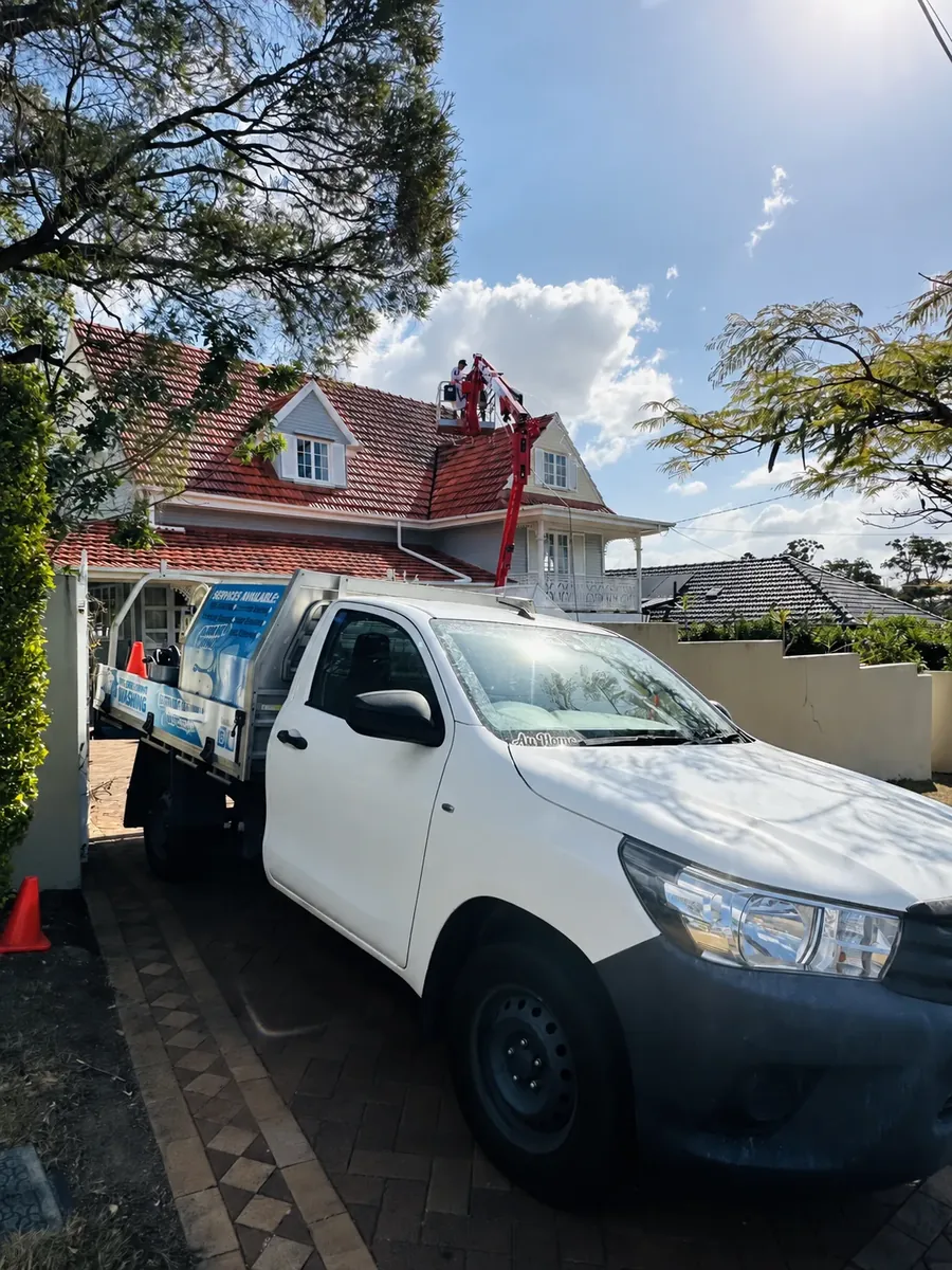 REEF Pressure Cleaning technician on a cherry picker cleaning the terracotta roof of a Gold Coast home